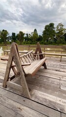 Close up A long wooden chair stands on a wooden bridge.