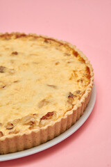 Savory quiche on pink surface: delicious pastry, cheese, and onion tart