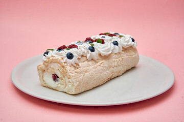 Delicious meringue roll with berries and cream on pink background