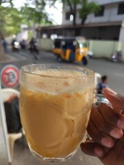 Refreshing mango shake served in a glass cup at a local juice shop on a street in Tamil Nadu, India. Captures authentic Indian street food culture and vibrant tropical flavors.