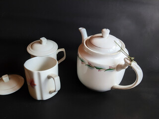 Ceramic kettles and saucers on a black background