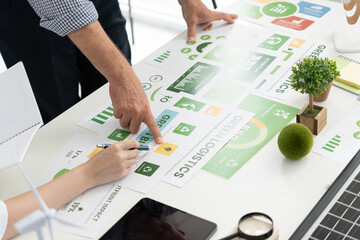 A diverse business team analyzing environmental charts and graphs in a collaborative meeting to create sustainable strategies in a modern office.