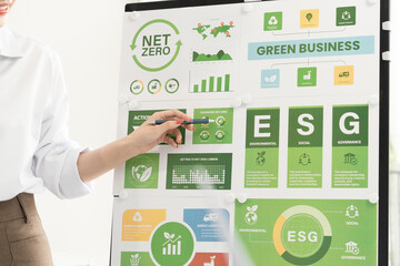 A diverse business team analyzing environmental charts and graphs in a collaborative meeting to create sustainable strategies in a modern office.