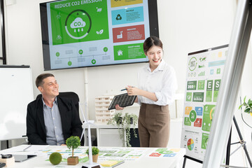 A diverse business team analyzing environmental charts and graphs in a collaborative meeting to create sustainable strategies in a modern office.