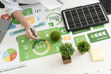 A diverse business team analyzing environmental charts and graphs in a collaborative meeting to create sustainable strategies in a modern office.