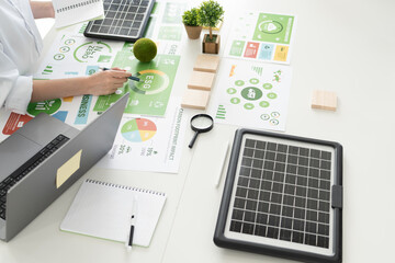A diverse business team analyzing environmental charts and graphs in a collaborative meeting to create sustainable strategies in a modern office.