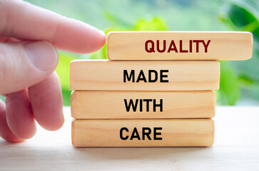 Quality made with care text on wooden blocks being gently pushed by hand represents thoughtful, intentional craftsmanship