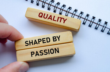 Quality shaped by passion text on wooden blocks over a notepad reflects teamwork driven by genuine...