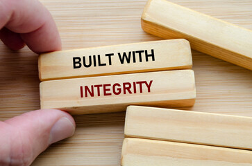 Built with integrity text on wooden blocks held by hand reflects trust, strength, and ethical values in every action