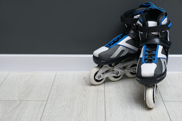 Pair of roller skates on floor near black wall, space for text