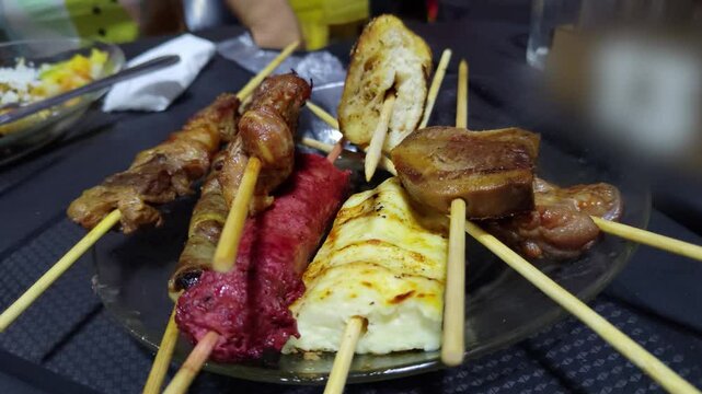 Assortment of traditional Brazilian barbecue skewers, including grilled cheese, sausage, meat, and garlic bread, served on a plate. Close-up of appetizers for a party or social gathering.