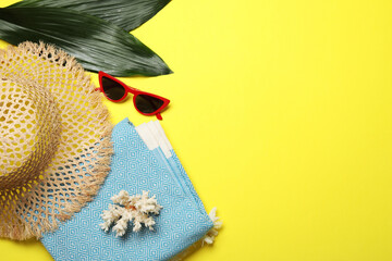 Flat lay composition with beach towel and other summer accessories on yellow background. Space for...