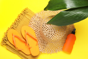Flat lay composition with beach towel and other summer accessories on yellow background