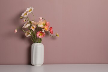 Beautiful poppy flowers in vase on white table against pink background. Space for text