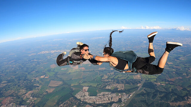 A heterosexual couple of skydivers kiss while free falling