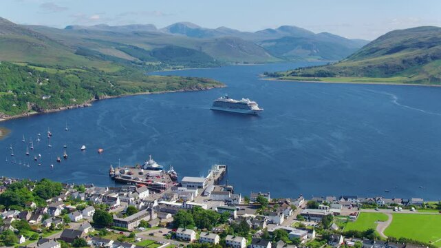 Drone shot of the Viking Sun cruise ship anchored in Loch Broom near Ullapool, surrounded by scenic Highland landscapes and calm waters on a clear, bright day.