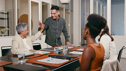 Obraz premium Diverse Business Team Celebrating Collaboration with High-Five During a Productive Meeting in a Modern Office Setting