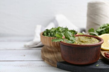 Tasty sauce with cilantro and other ingredients on white wooden table, closeup. Space for text