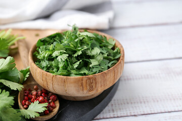 Fresh green cilantro and peppercorns on white wooden table, closeup. Space for text