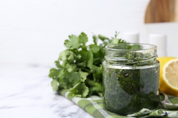 Tasty sauce with cilantro and lemon on white marble table, closeup. Space for text