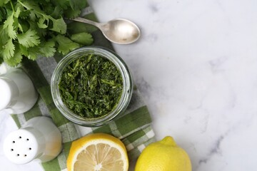 Tasty sauce with cilantro and lemons on white marble table, flat lay. Space for text