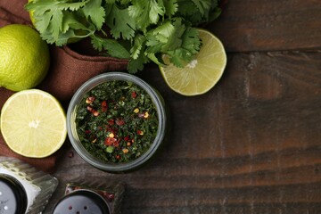 Tasty sauce with cilantro and limes on wooden table, flat lay. Space for text