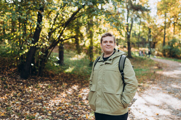 Calm happy 30s Man Relaxing in Autumn Park Outdoors. Traveler. Falling time. Smiling man in casual clothing standing outdoor