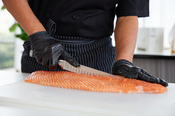 Chef slicing raw salmon fish in the kitchen