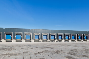 Obraz premium Modern industrial logistics warehouse row of closed loading docks with metal shutter doors for freight transport