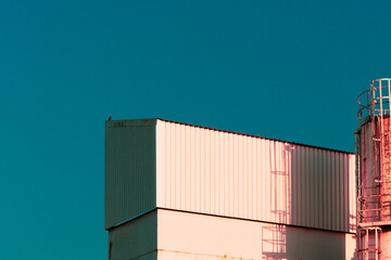 an infrared like vaporwave edit. Industrial warehouse building with a ladder against a aqua blue copyspace sky