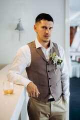 portrait of the groom in a gray suit and an orange vest