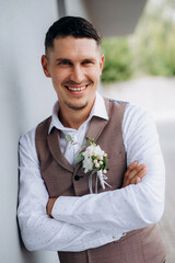 portrait of the groom in a gray suit and an orange vest