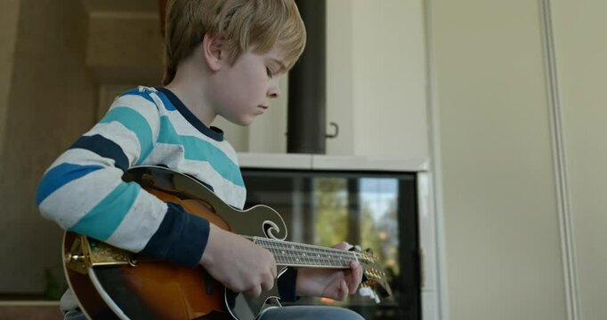 Caucasian Kid Play Mandolin at Home. European Boy Practice Music 4K 10-bit