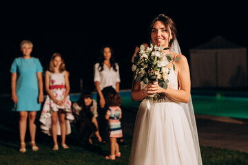 bride in a white dress throws a wedding bouquet