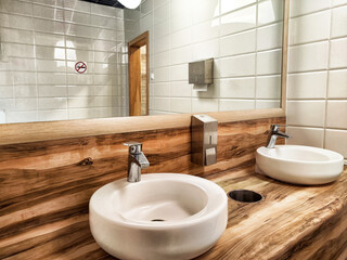 This contemporary bathroom showcases an exquisite combination of distinctive wooden and ceramic sinks, beautifully highlighting minimalist design features.