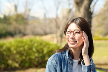 公園で微笑むメガネをかけた日本人女性