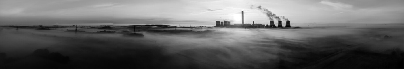 Panoramic aerial view of Drax Power Station in black and white, shrouded in fog with plumes rising...