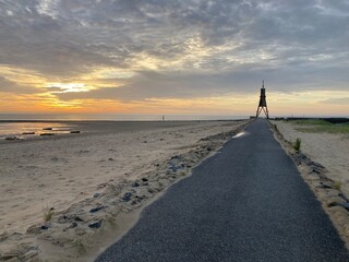 Sonnenaufgang am Strand von Cuxhaven an der Nordsee mit Blick auf die Kugelbake und Promenade