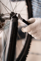 Close-up of male mechanic working in bicycle repair shop repairing bike using special tool