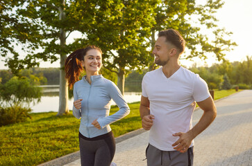 Happy sporty friendly people actively running outdoors, healthy looking couple jogging enjoying fit...