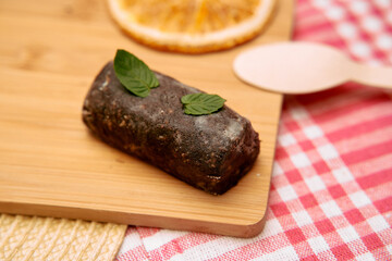 Chocolate ganache log with mint leaves on wooden board with red gingham cloth