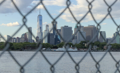downtown manhattan new york city skyline seen through metal chain link fence from red hook brooklyn...
