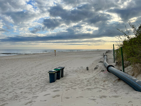 The eastern beach in Mrzezyno, Poland, with a pipe that is sometimes attached to the port dredger to drain sand from the dredging to the beach