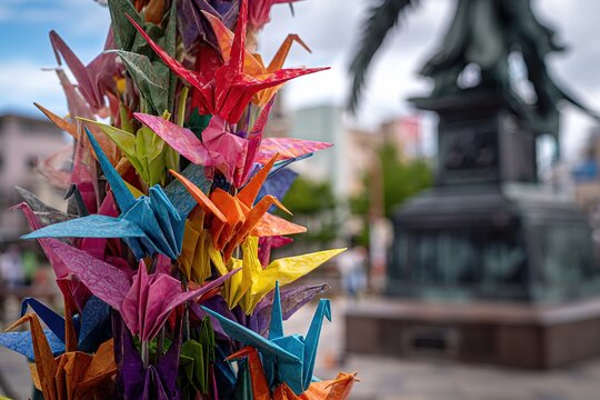 Close-up of colorful origami cranes hanging around a statue in Hiroshima 