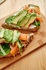 Delicious avocado and veggie toast on wooden board for a healthy meal