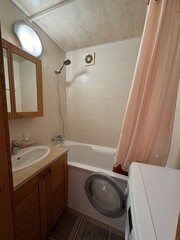 Small Bathroom with Bathtub, Washing Machine and Wooden Cabinet