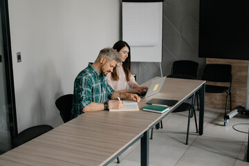 Focused coworkers collaborating at a long desk in a contemporary workspace.