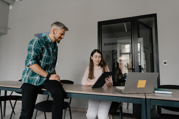Two professionals working together with a tablet and laptop in a contemporary office