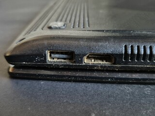 Close-up view of old and dusty USB ports on black laptop side panel