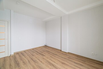 Obraz premium bright, empty room with wood-like flooring, white walls, and a white door with horizontal glass panes, creating a clean and minimalist aesthetic